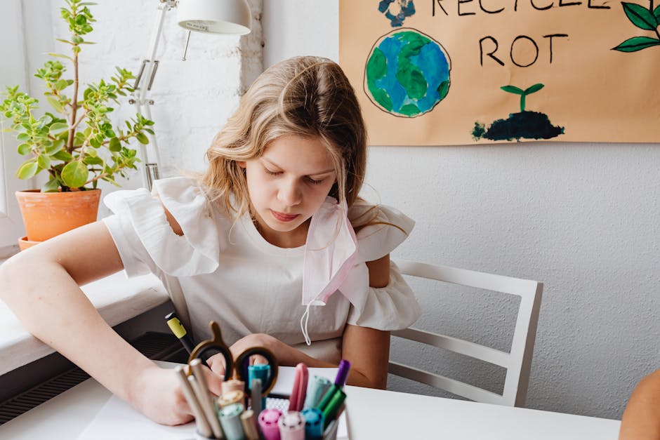 A young girl in a white dress writes at a desk surrounded by school supplies and a recycling poster.
